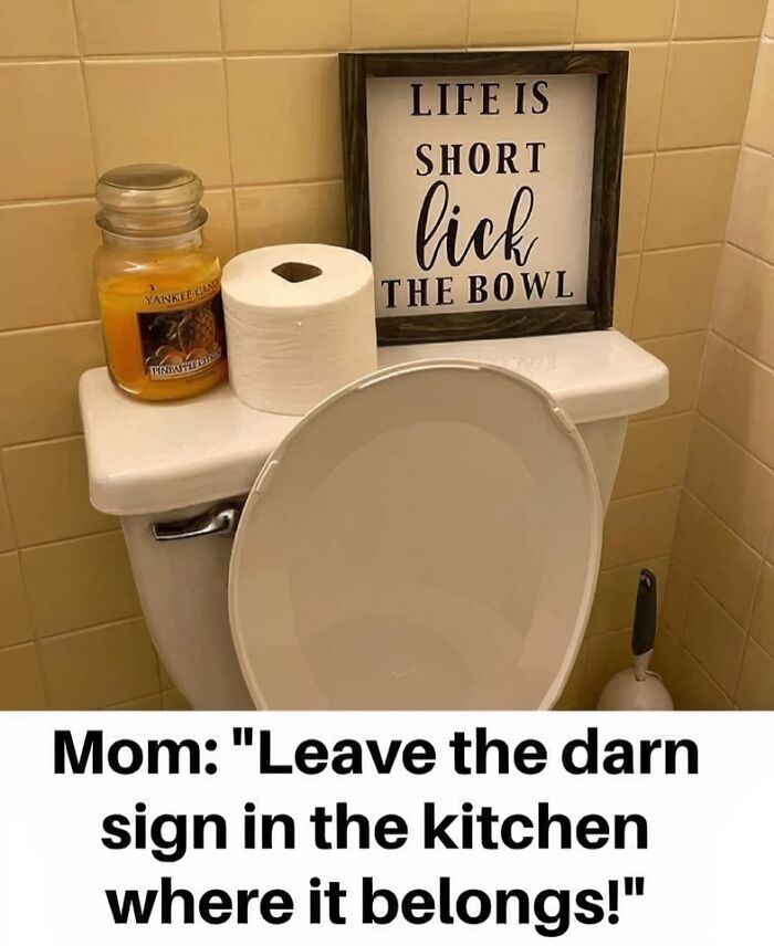 Bathroom with a humorous sign saying life is short lick the bowl, a candle, and toilet paper on the tank.