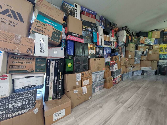 Large collection of boxed video games and collectibles stacked along a room wall showing obsession turned into collection