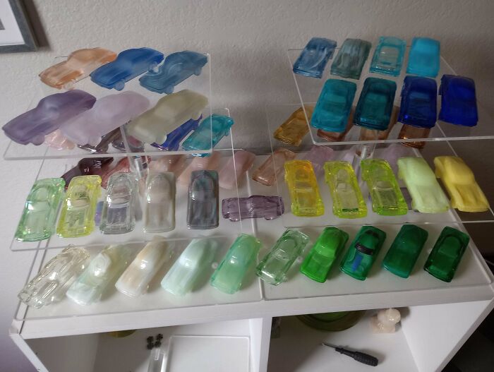 Collection of colorful translucent toy cars displayed on clear shelves, showcasing a unique and growing obsession.