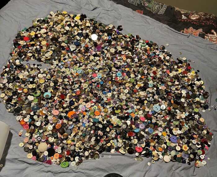 A large collection of colorful buttons spread out on a bed, showcasing obsessive button collecting.