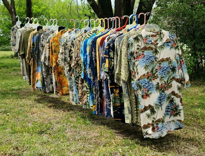 A collection of colorful Hawaiian shirts hung outdoors, showing a vibrant obsession with unique clothing pieces.