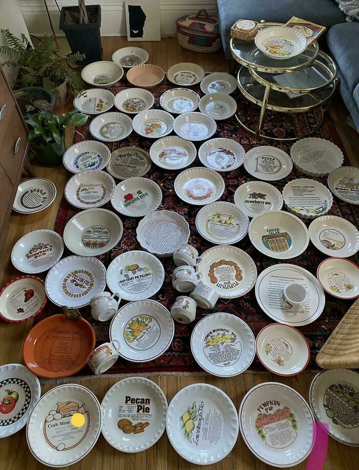 Collection of decorative pie plates with recipe prints displayed on a rug showing obsession turned into collection.