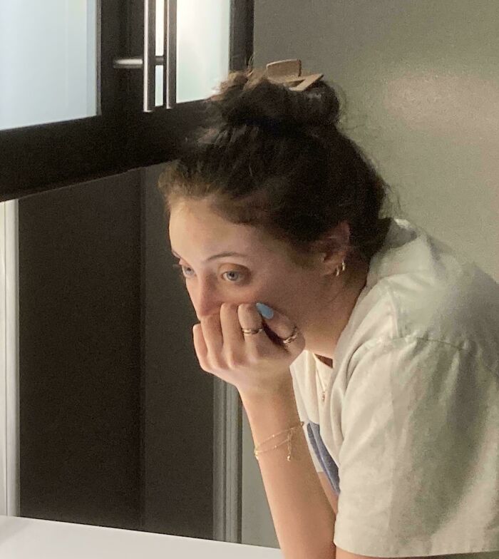 A pensive young woman with her hand on her chin in a candid photo with Accidental Renaissance lighting