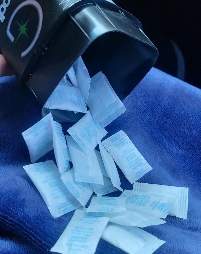 Black container spilling many silica gel packets on blue fabric illustrating disappointing shopping fails.