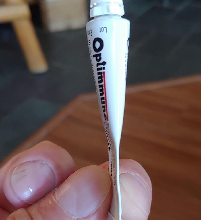 Close-up of a hand holding a damaged Optimum tube, showcasing a disappointing shopping fail causing trust issues.