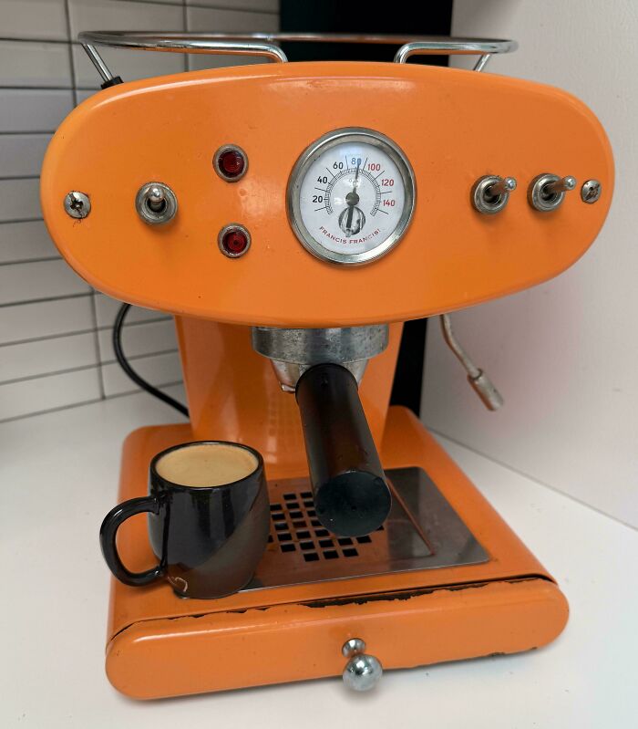 An orange retro espresso machine with a black cup, a fantastic jackpot score from a thrift store.