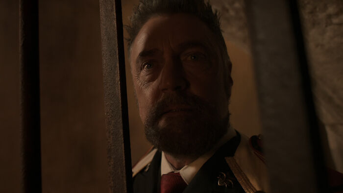 Man with beard and uniform behind bars in dark setting, evoking suspense related to One Piece season 2 game-changing reveal.