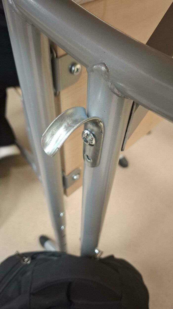 A metal handle attached to a desk, but the handle is facing the wrong way, making it a funny 'you had one job' fail.