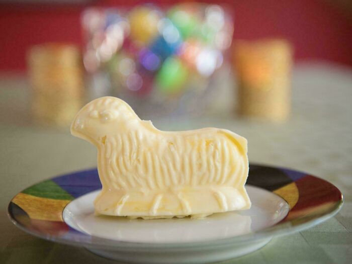 Butter sculpture shaped like a lamb on a colorful plate, representing weird family traditions around food and holidays.