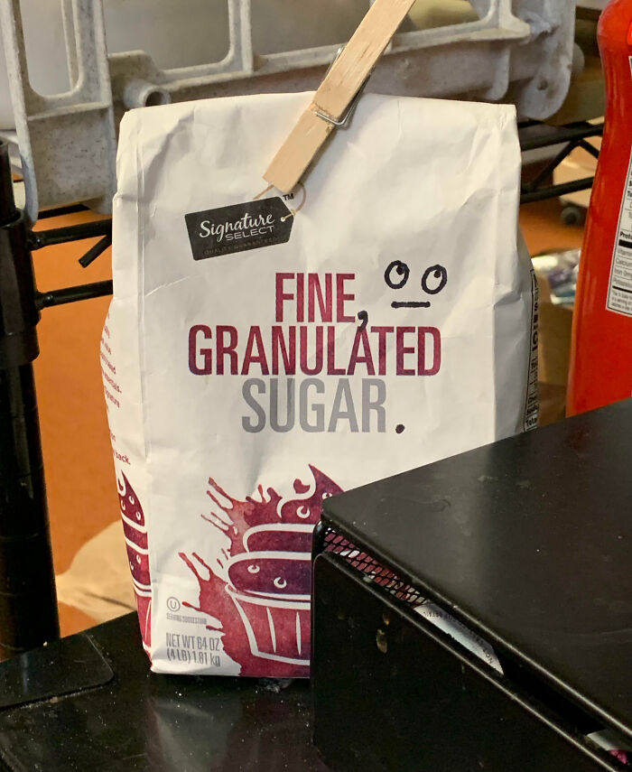 Bag of fine granulated sugar with a small face doodle drawn as mild vandalism on the packaging.
