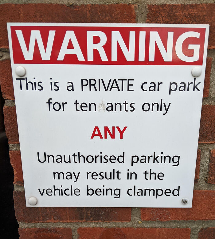 Warning sign on brick wall with mild vandalism altering private car park text, illustrating mild vandalism humor.