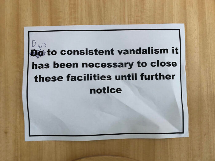 Paper sign on wooden door explaining closure of facilities due to consistent mild vandalism until further notice