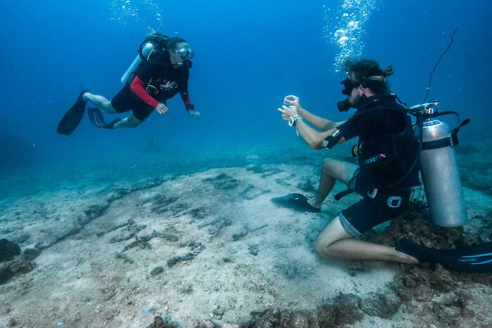 Two scuba divers exploring underwater ruins showcasing incredible reality beneath the sea surface.