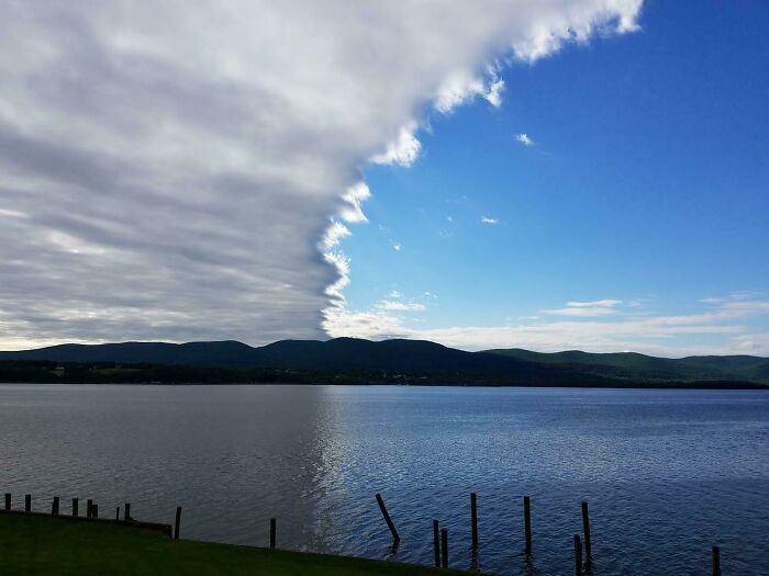 Unreal photo of a lake showing dramatic contrast between cloudy and clear sky, illustrating incredible natural phenomena.