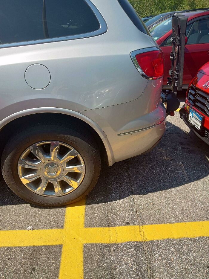 Silver SUV parked over yellow lines, blocking space, illustrating entitled Karens lacking a sense of shame in parking behavior.