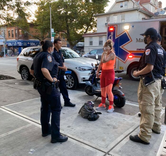 Police officers question a woman on the street near an ambulance, highlighting entitled Karens missing a sense of shame.