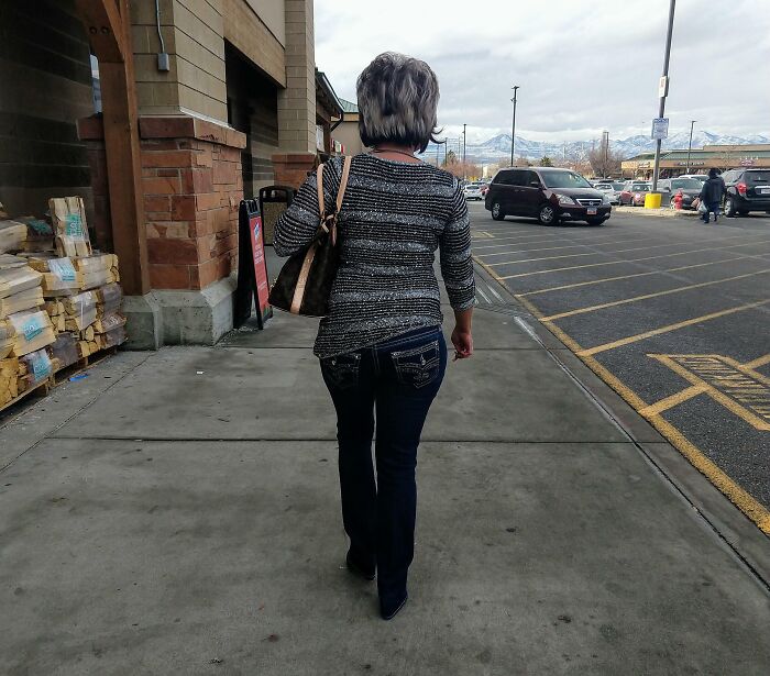 Woman walking on sidewalk outside store carrying a handbag, illustrating entitled Karens missing a sense of shame concept.