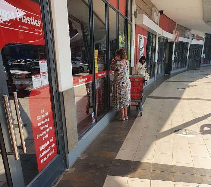 Woman standing outside a store with a shopping cart, illustrating entitled Karens lacking a sense of shame in public behavior.