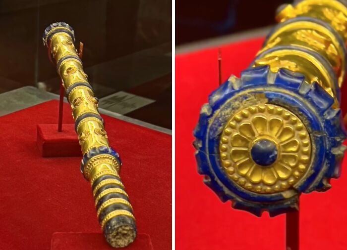Antique gold and blue ornamental staff almost perfectly preserved on red display, showcasing history secrets.