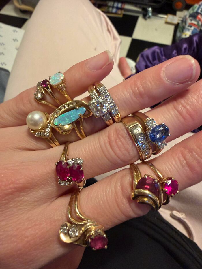 A hand adorned with multiple ornate rings, showcasing a jackpot of jewelry found at a thrift store.