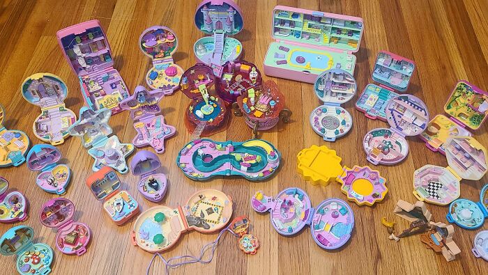 Collection of colorful vintage Polly Pocket toys displayed on wooden floor showing people’s obsession collection