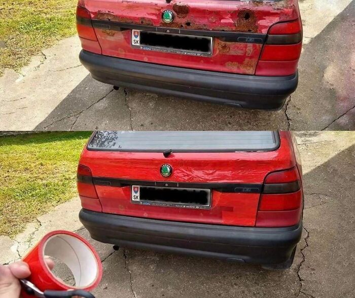 Red car with a badly damaged trunk repaired using red tape, showing a technically works but dumb solution to a problem.