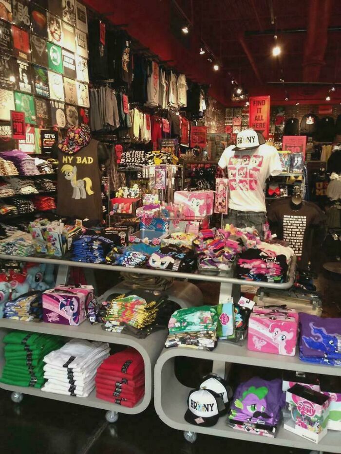 Retail store filled with 2010s merchandise including My Little Pony clothing, hats, and nostalgic pop culture items.