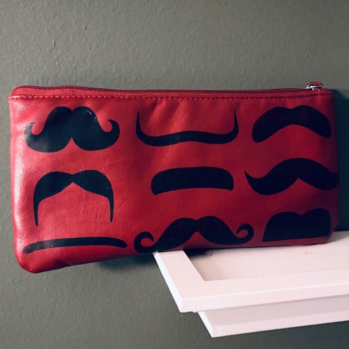 Red zippered pouch with various black mustache designs, evoking nostalgia and memories from the 2010s decade.