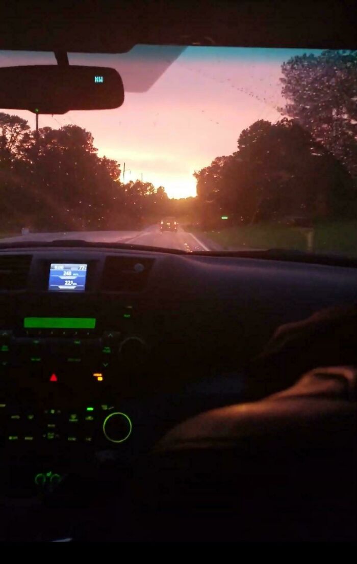 View from inside a car driving towards a sunset, capturing a nostalgic moment from the 2010s era.