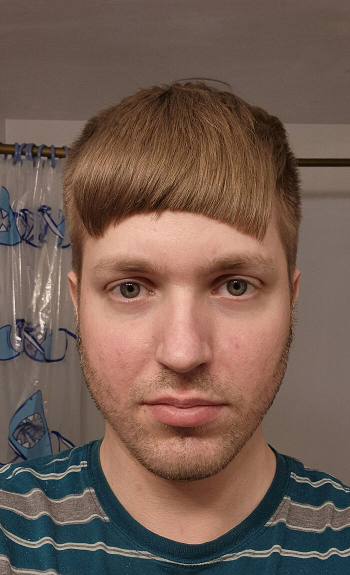 Man with uneven blunt haircut looking at camera, example of hairdresser mistakes traumatizing hair locks.
