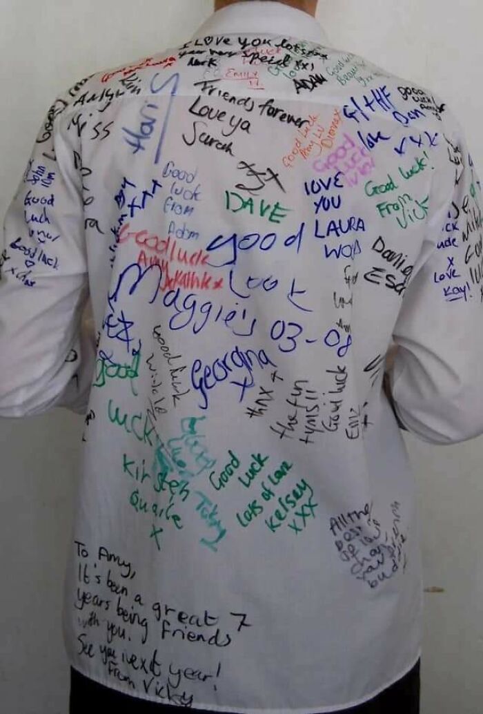 Person wearing a white shirt covered in colorful handwritten messages and signatures, reflecting 2010s nostalgia.