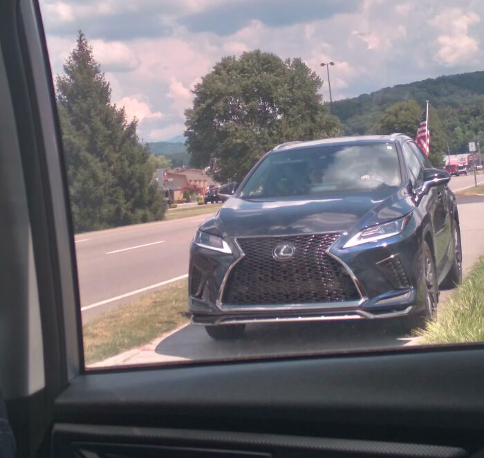 Black Lexus SUV parked on the roadside with an American flag, part of a story about entitled Karens and public reactions.