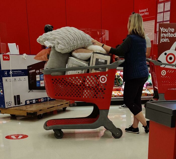 Woman pushing a Target shopping cart full of pillows and home goods, illustrating entitled Karens behavior in retail settings.