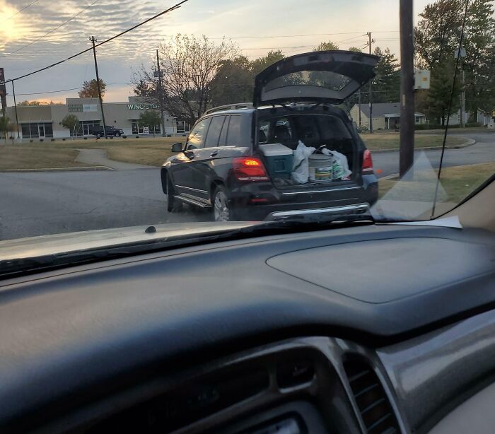 Black SUV with an open trunk full of items parked on a suburban street at dusk, capturing entitled Karens behavior context.