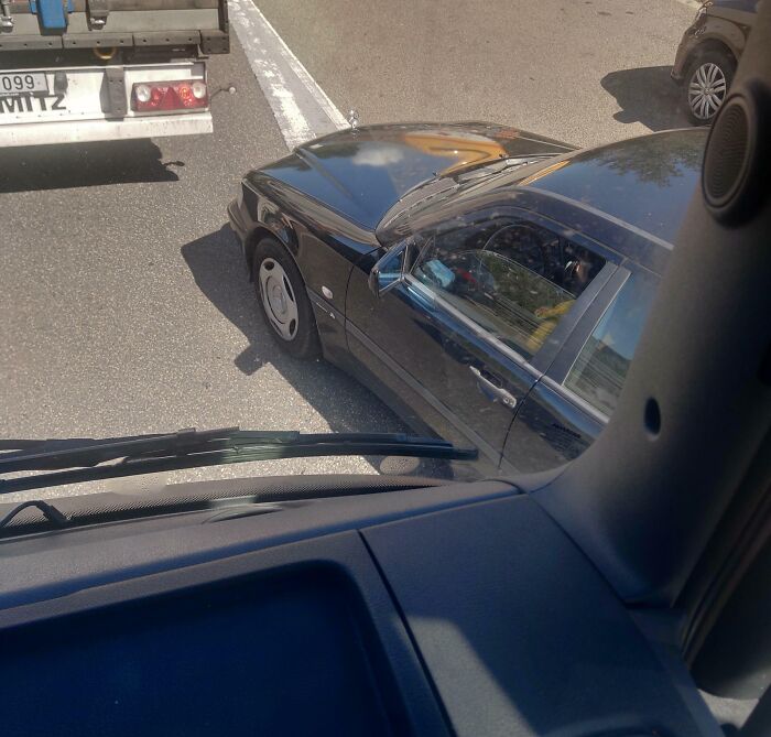 Black car blocking traffic on a busy road, illustrating entitled behavior often associated with Karens in public settings.
