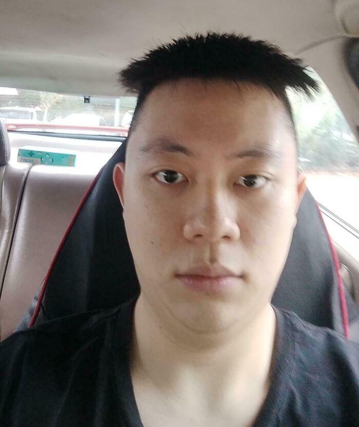 Man sitting in a car with a shocked expression and uneven, traumatizing haircut from a hairdresser mistake.