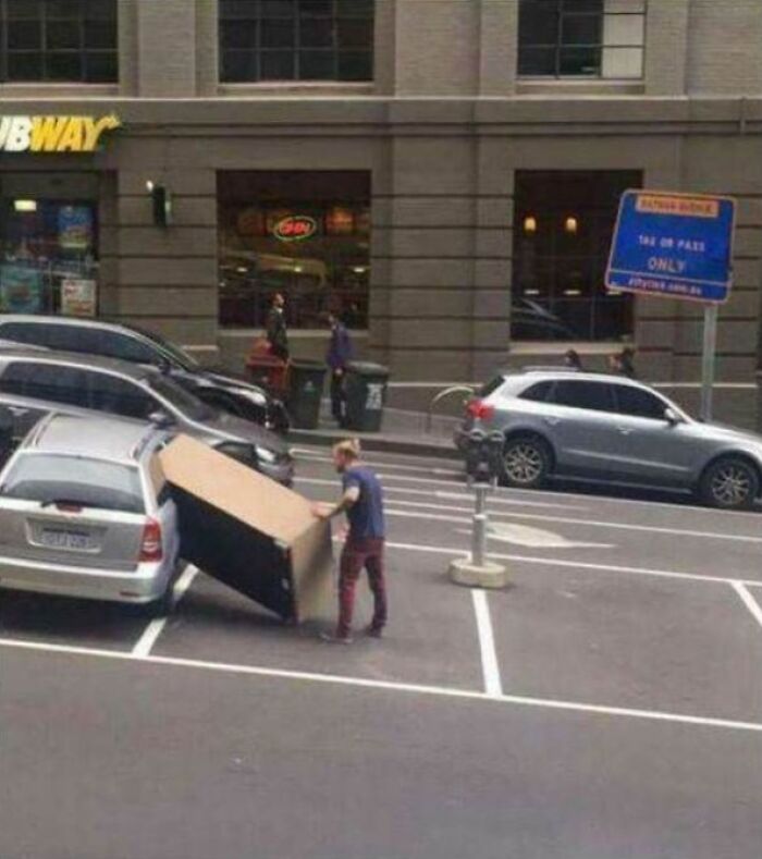 Man attempting to load large furniture into a small car, illustrating forgetful disasters and what could go wrong moments.