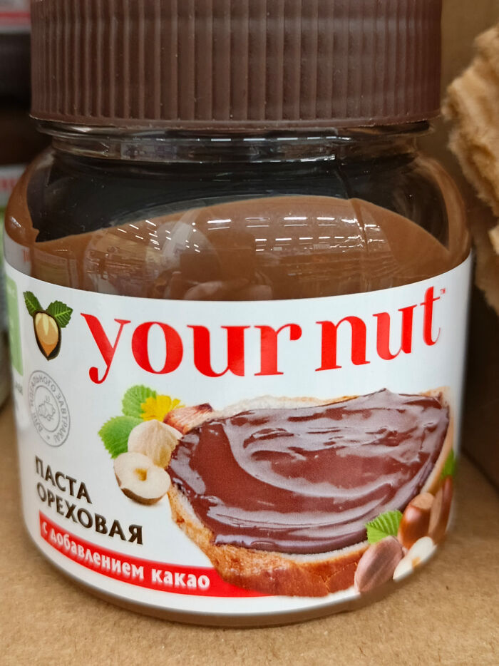Jar of hazelnut spread labeled your nut resembling famous brand packaging with chocolate and nuts on label.