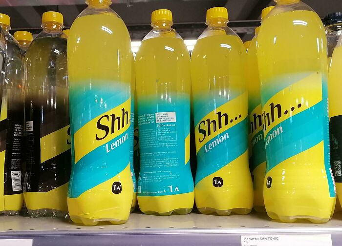 Plastic bottles of a lemon-flavored drink with a label design copying famous brands, shown on a store shelf.