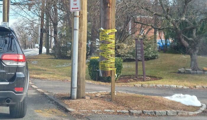 Car wrapped in caution tape on a pole, demonstrating a technically works but hilariously dumb solution to a problem.