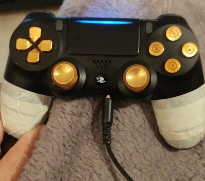 PlayStation controller with taped handles and gold buttons, a technically works but makeshift gaming solution.