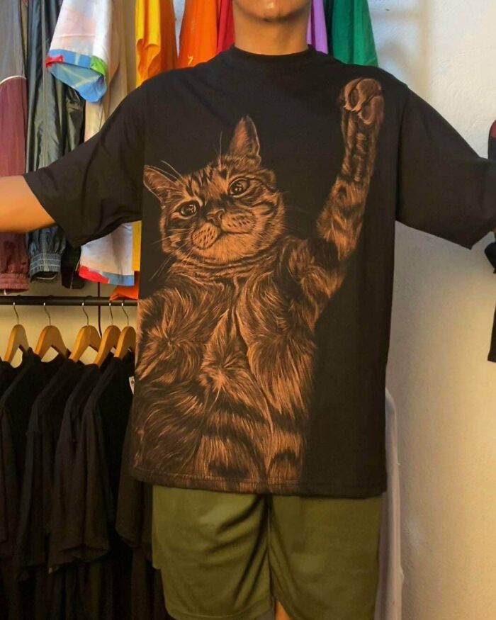 Person wearing black t-shirt with detailed cat design, showcasing a creative DIY win in a colorful clothing space.