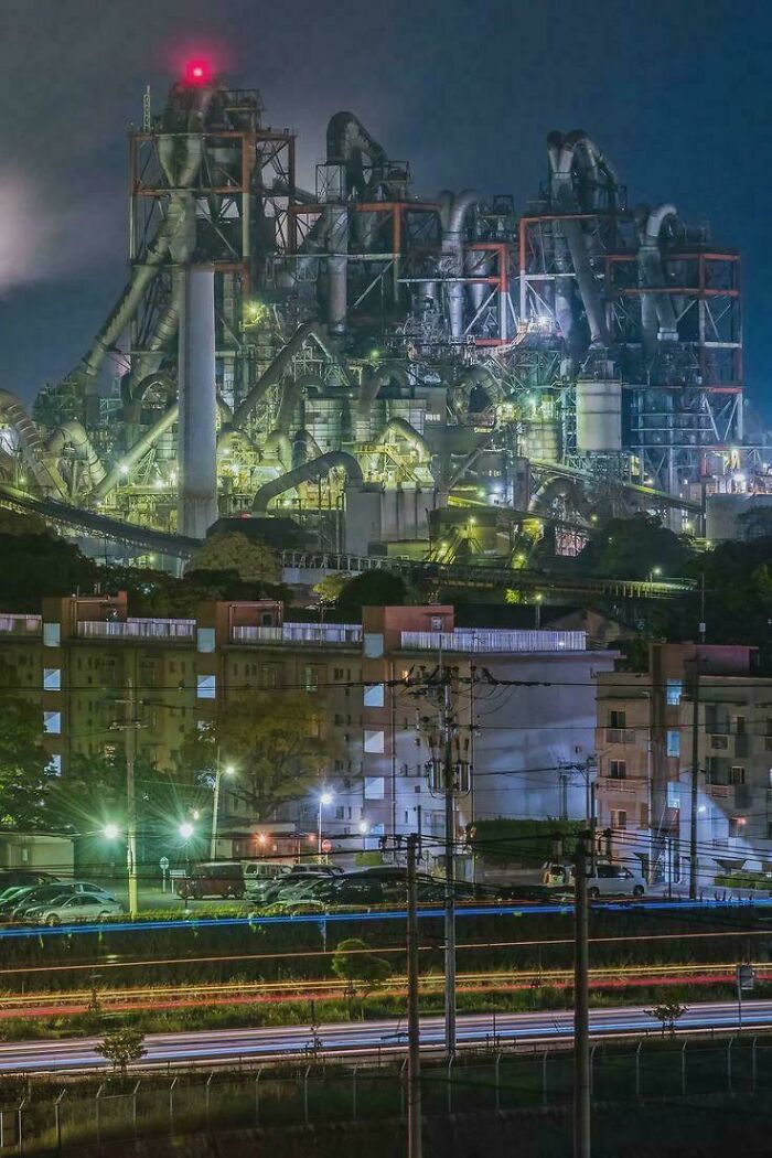 An industrial complex with many pipes and lights at night, appearing as a base for an evil mastermind.