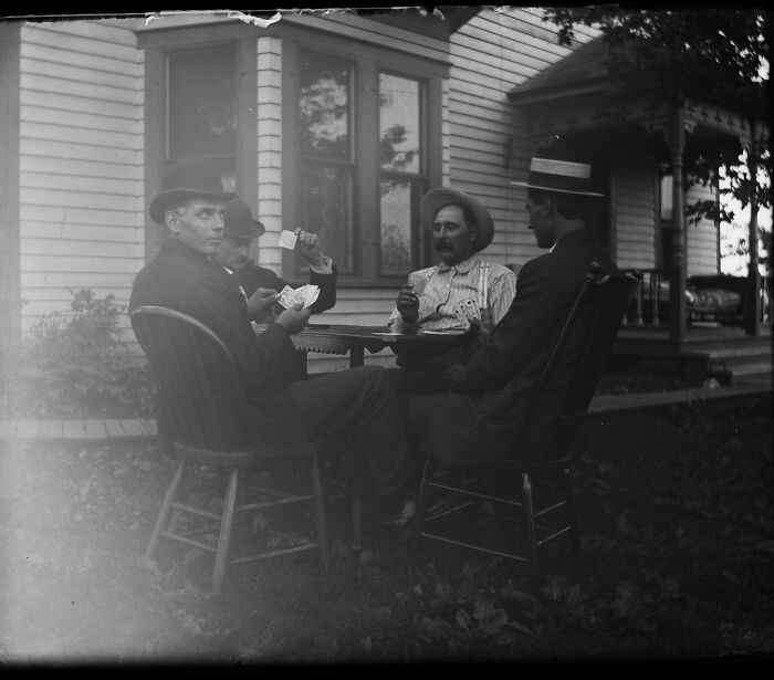 A candid old photo of four men playing cards outdoors, revealing what the world looked like generations ago.