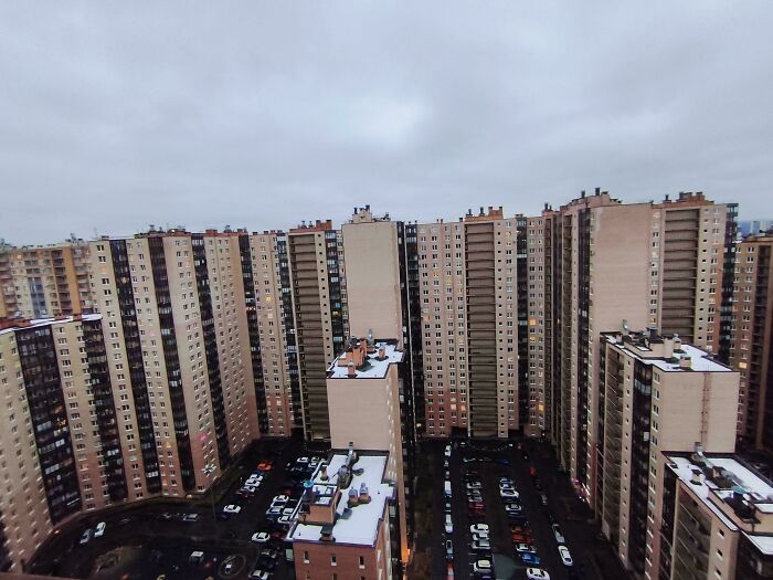 High-rise urban hell apartment complex under cloudy sky with parking lot below