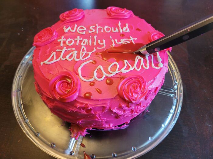 Pink frosted cake with humorous text and knife cutting through dessert