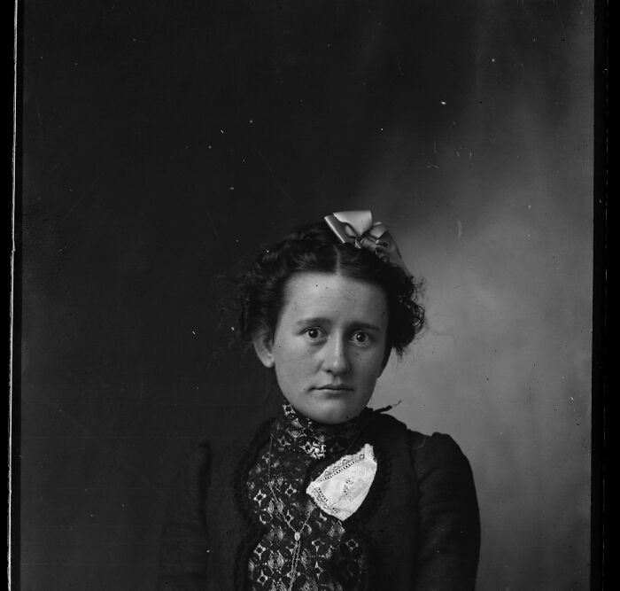 A candid old photo of a serious woman with a bow in her hair, revealing what the world looked like generations ago.