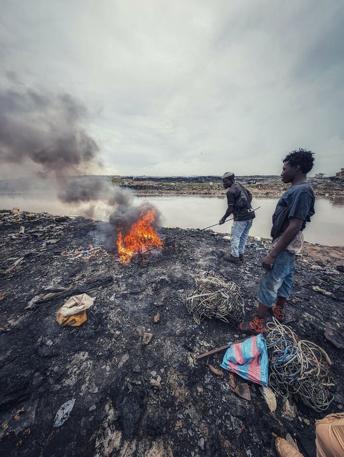 Urban hell site with people burning waste amidst polluted landscape