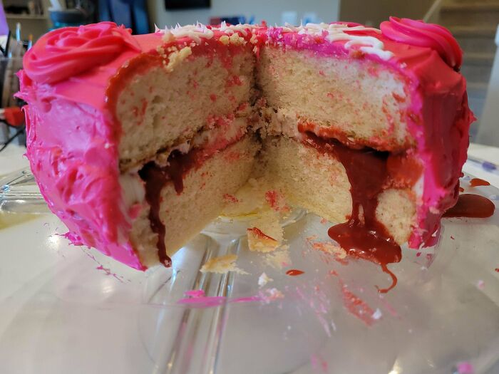 Pink frosted cake with chocolate filling oozing from the center slice dessert