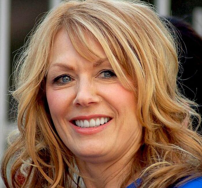 Nancy Wilson smiling outdoors with blonde hair, showcasing a confident and approachable look for bio and career highlights.